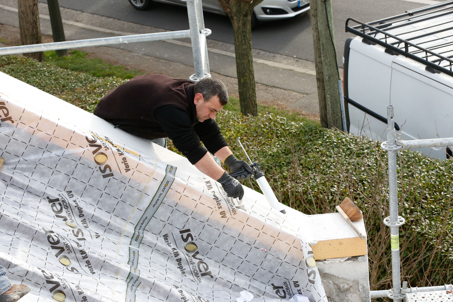 Technicien installant l'adhésif Isover Vario Multitape sur une membrane d'étanchéité à l'air Isover en extérieur