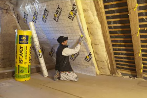 Ouvrier installant une membrane pare-vapeur Vario Duplex Isover dans les combles