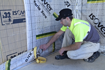 Technicien installant une Vario Xtra Band Isover sur une membrane d'étanchéité Isover